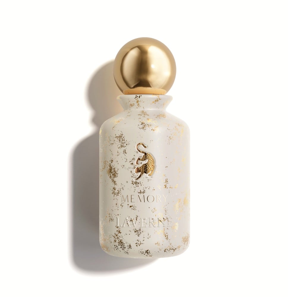 زجاجة عطر "ميموري" من لافيرن. الزجاجة بيضاء غير لامعة (مطفي) ومزينة برشّات أو رذاذ ذهبي غير منتظم، مما يعطيها مظهر الغيوم الذهبية أو الرخام. غطاء الزجاجة معدني وكروي باللون الذهبي اللامع. يوجد في منتصف الزجاجة شعار لافيرن (شكل يشبه النمر الرابض) مطلي باللون الذهبي، ومكتوب أسفله اسم "MEMORY" ثم "LAVERNE" باللون الذهبي. العطر محايد ومناسب للاستخدام اليومي، ويحتوي على نوتات عليا من التفاح والبرغموت، وقلب من خشب الأرز والورد، وقاعدة من المسك الأبيض والعنبر.